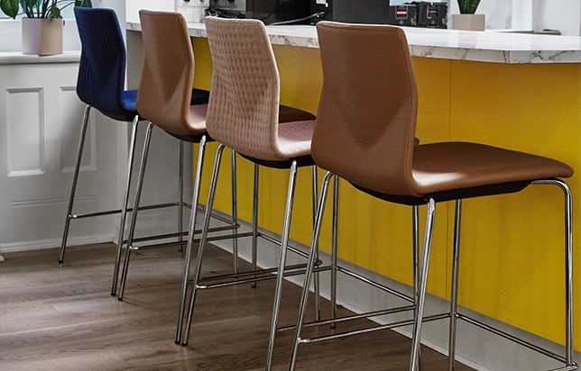 Four counter chairs in a kitchen with yellow walls.
