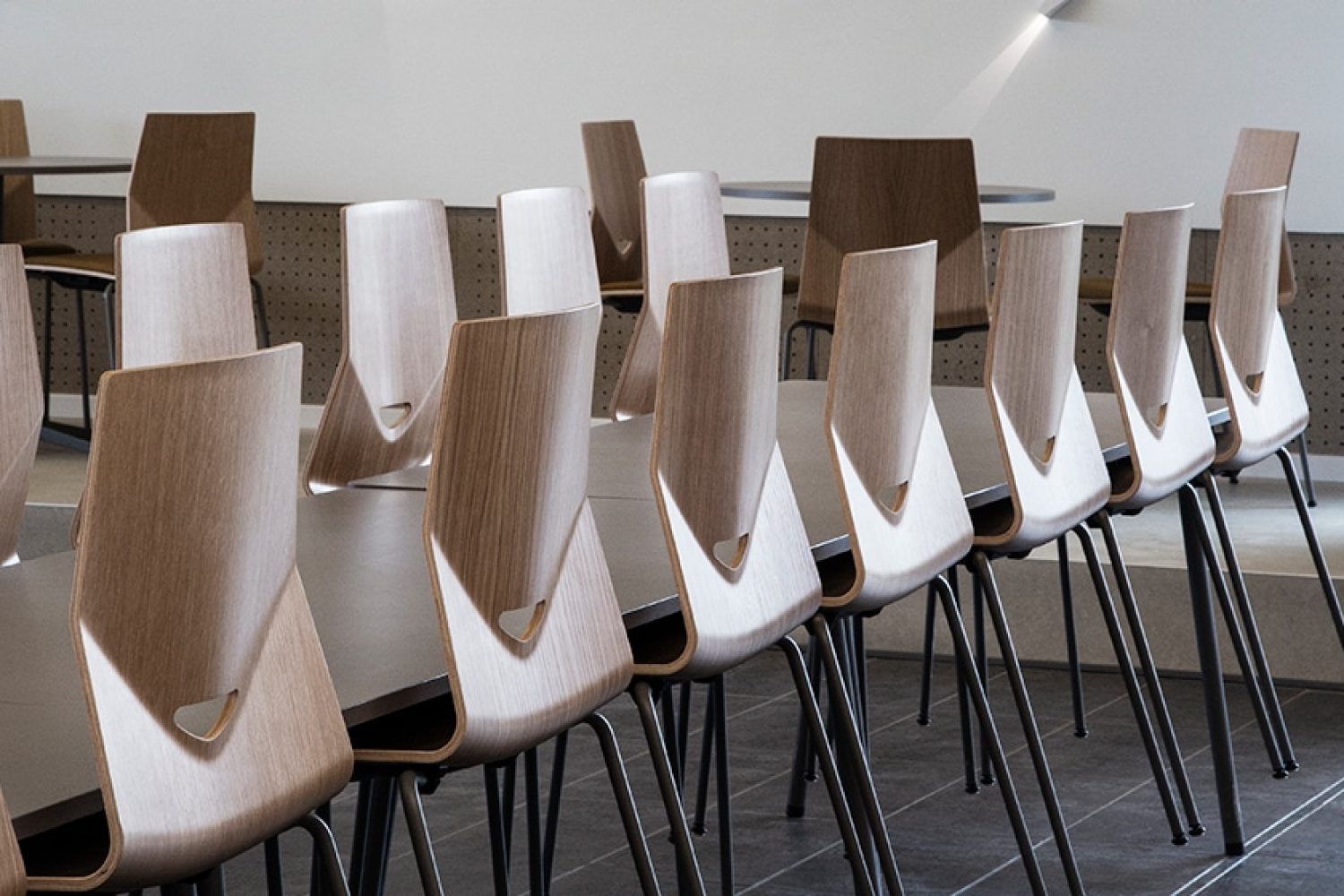 A row of wooden light weight office chairs in a conference room.