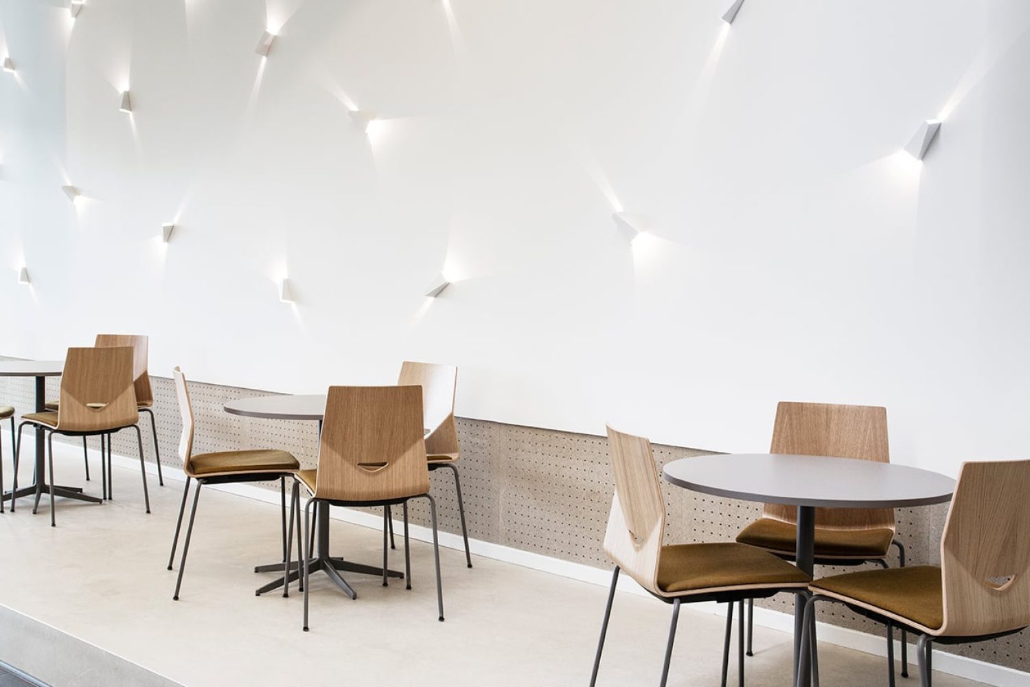 Office tables and chairs in front of a white wall.