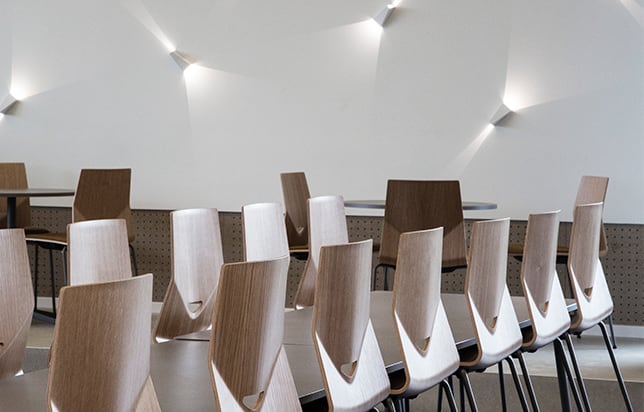 A row of wooden light weight office chairs in a conference room.
