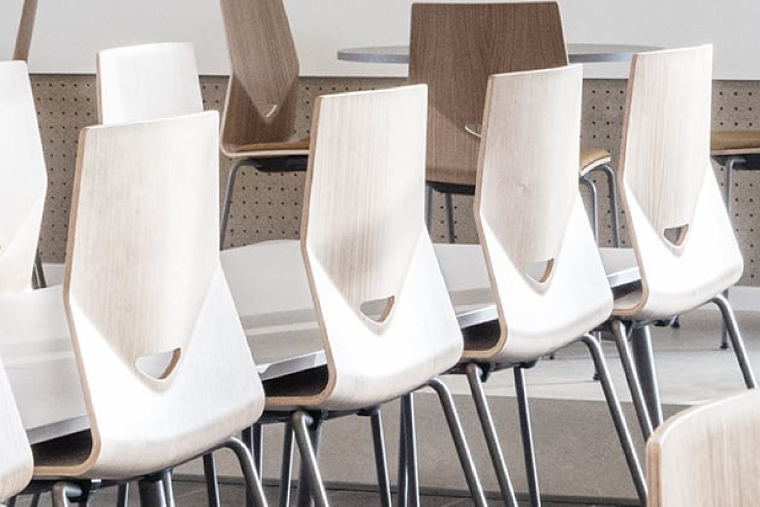 A row of wooden light weight office chairs in a conference room.