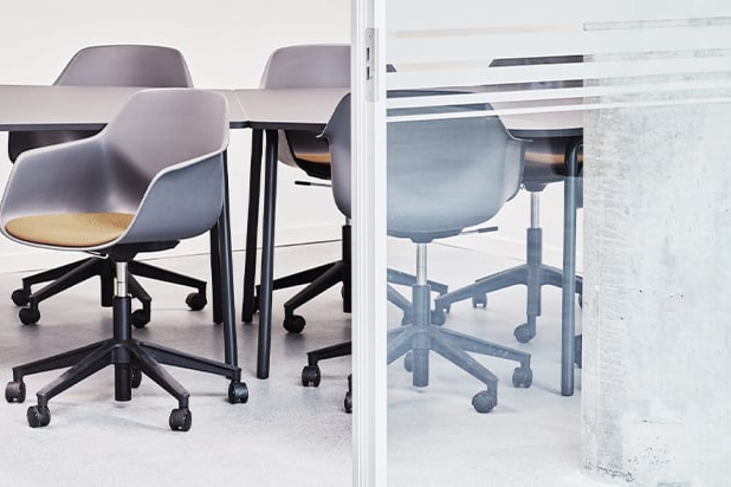 A group of chairs in a conference room with a glass partitian. 