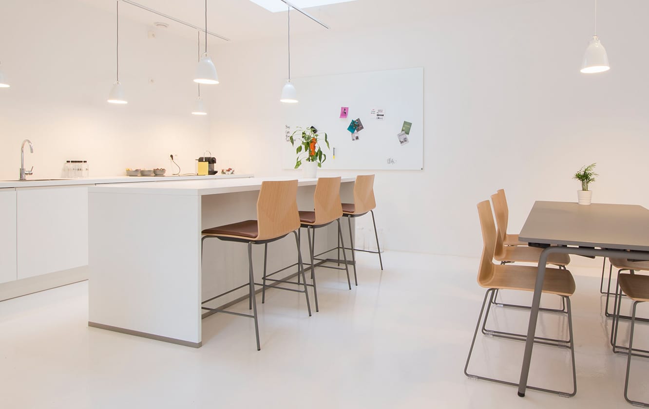 A white kitchen with standing height tables and counter chairs