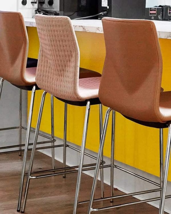 A row of counter chairs in a yellow kitchen.