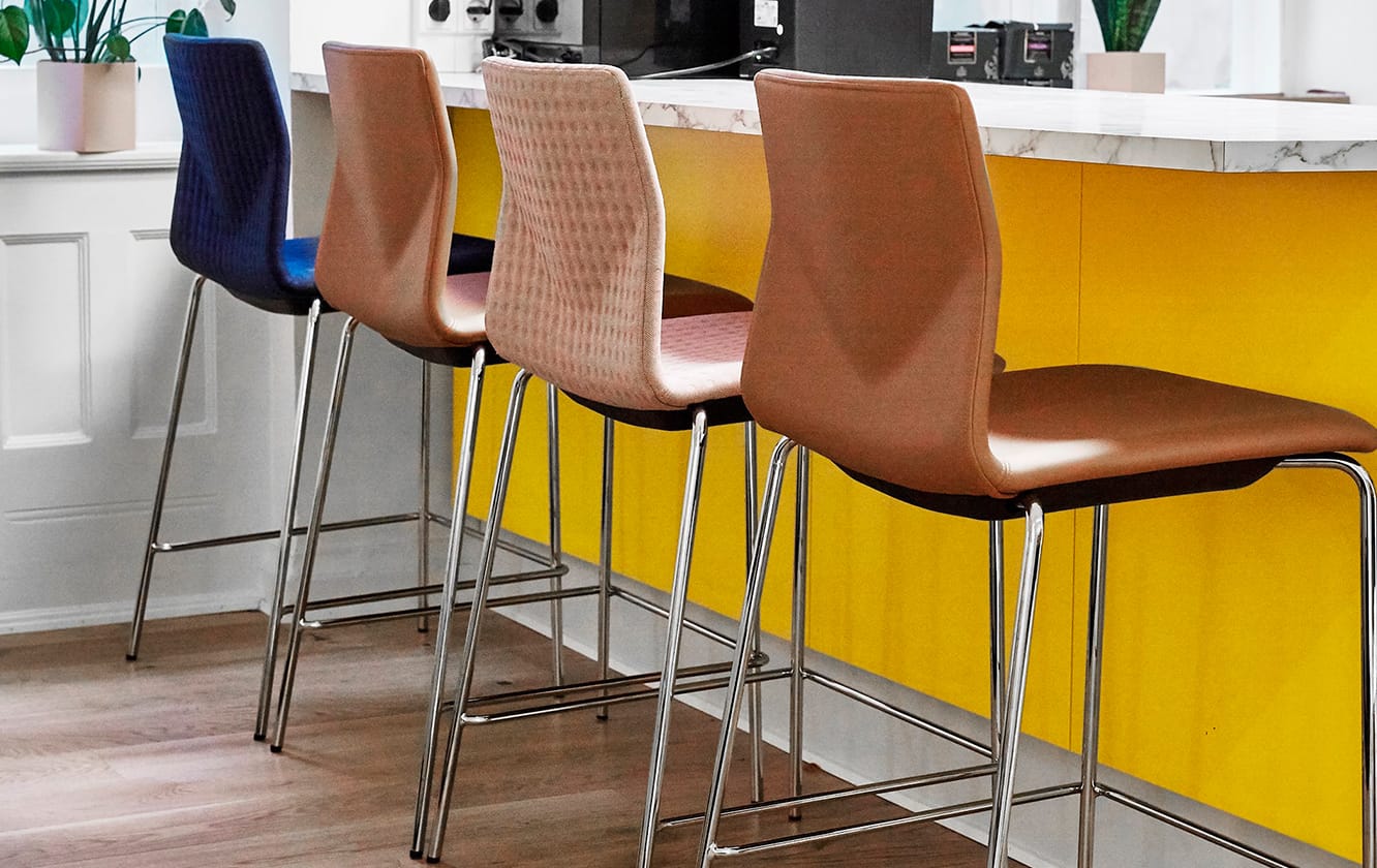 A row of counter chairs in a yellow kitchen.