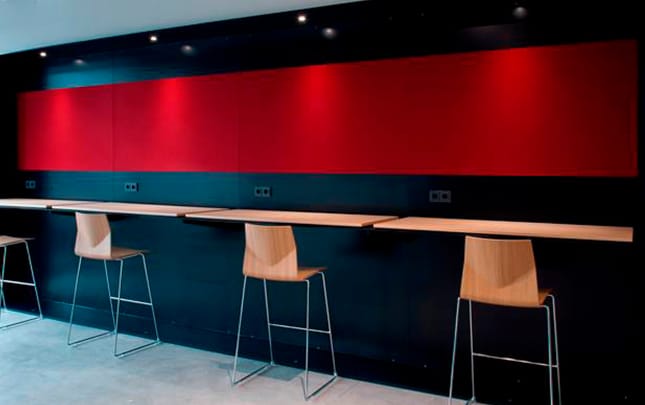 A bar with counter chairs and a red wall.