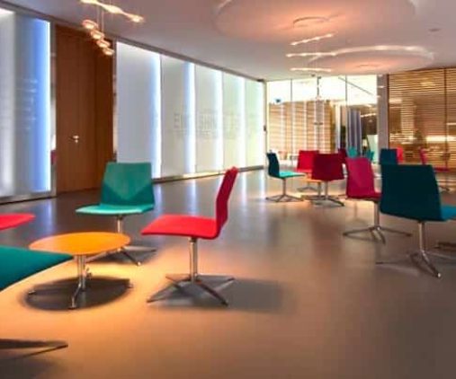 A lobby with colourful chairs and a glass wall.