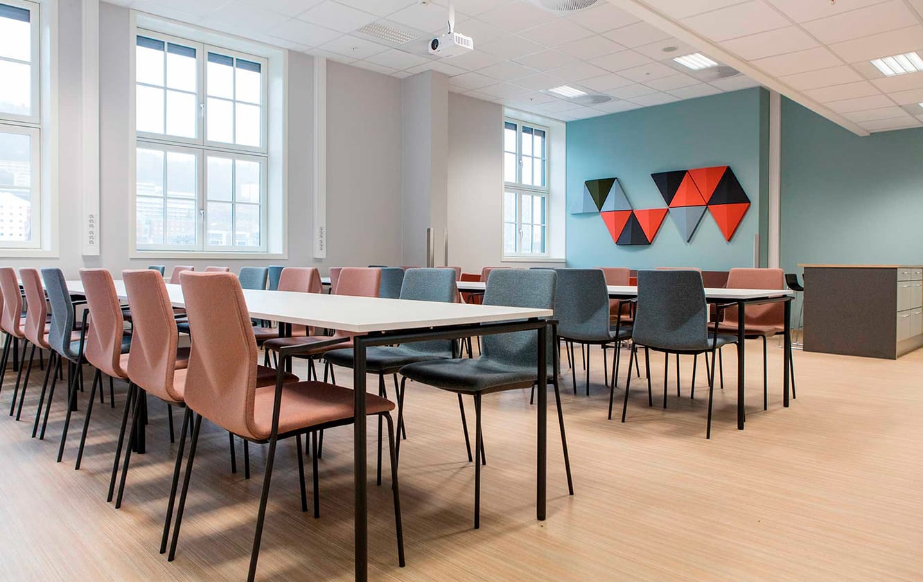 A classroom with tables and chairs in it and acoustic panels for offices on the wall.