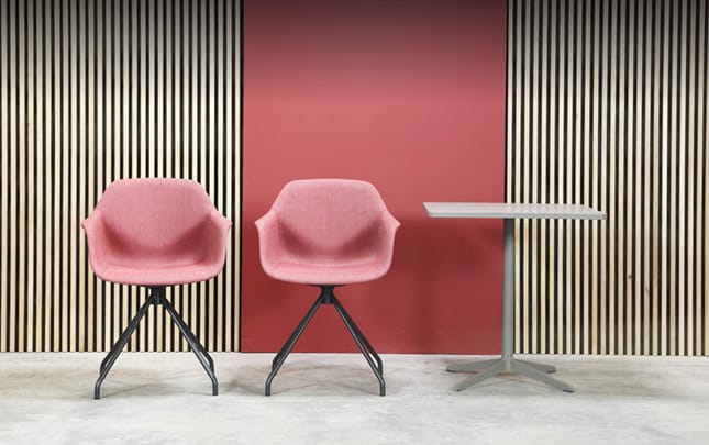 Two pink chairs in front of a striped wall.
