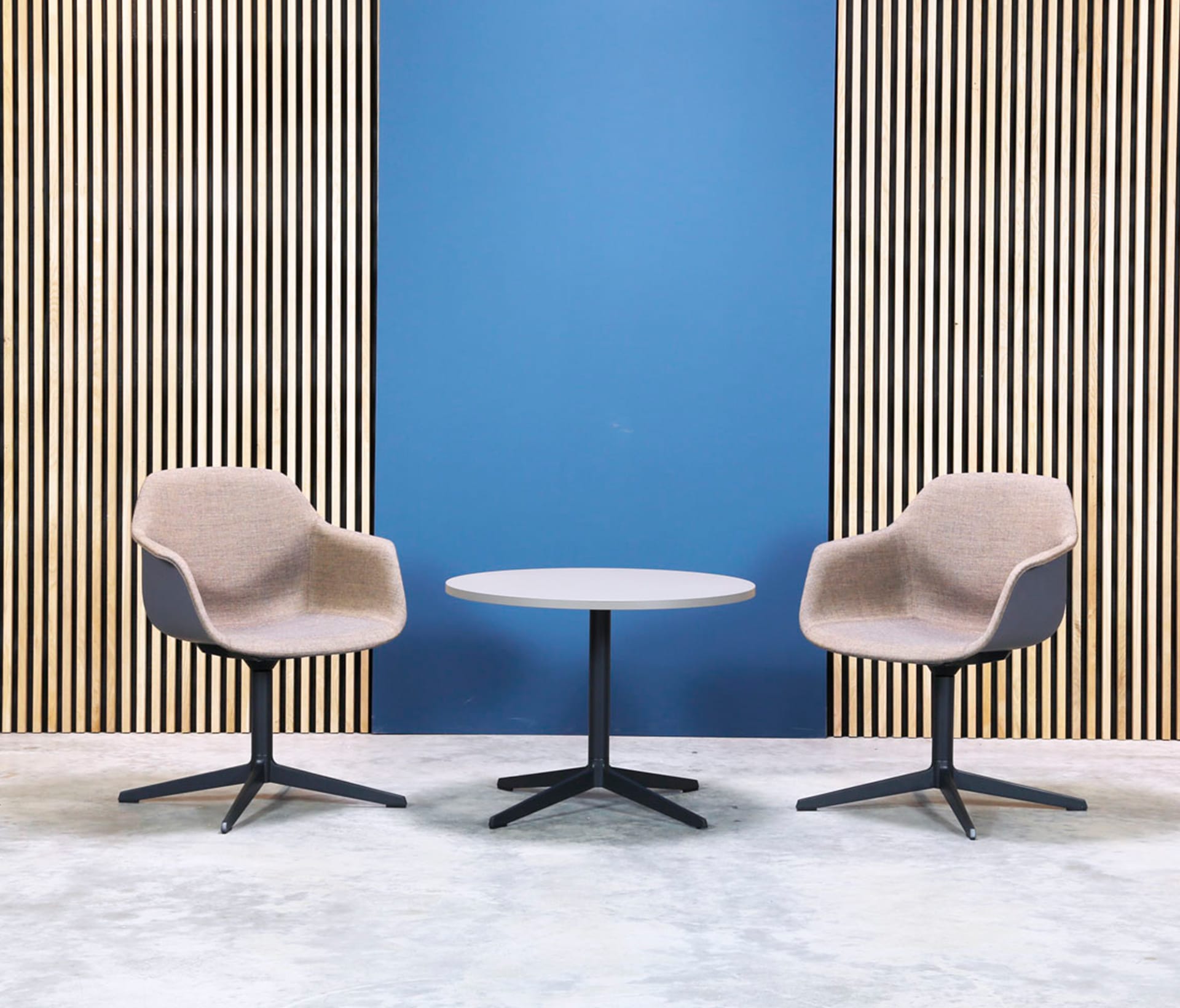 Two chairs and a table in front of a blue wall.