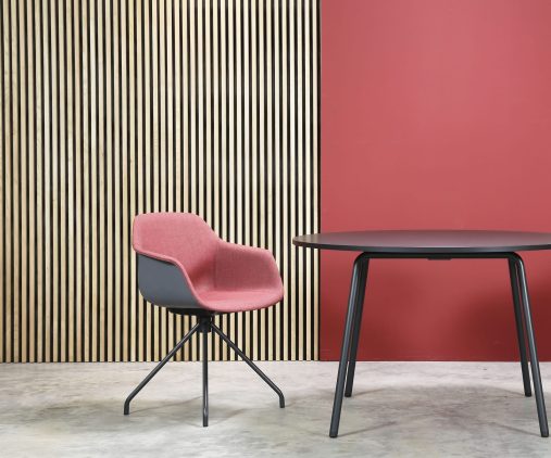 A table and chairs in front of a red wall.