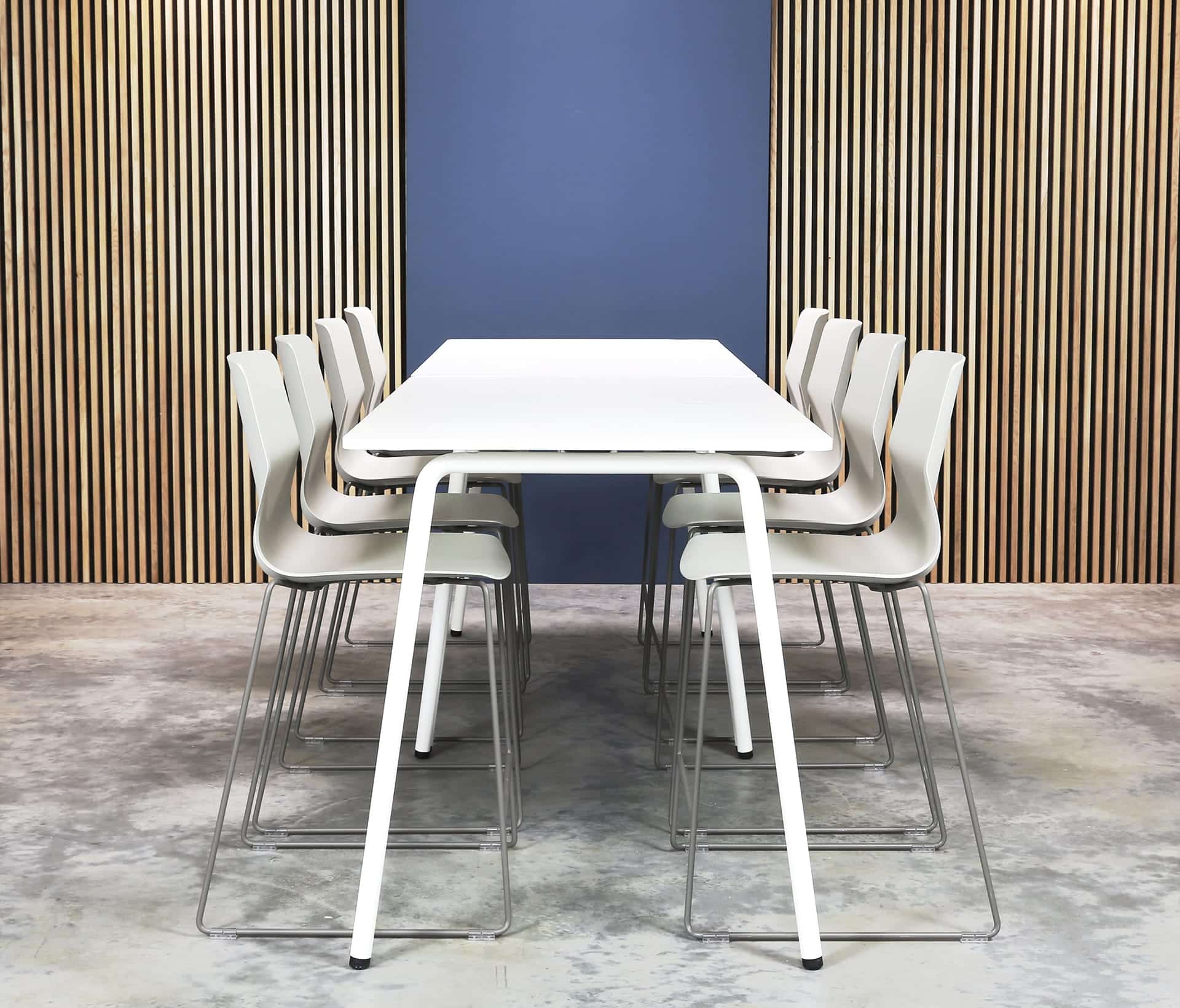 A white table and counter chairs in front of a wooden wall.