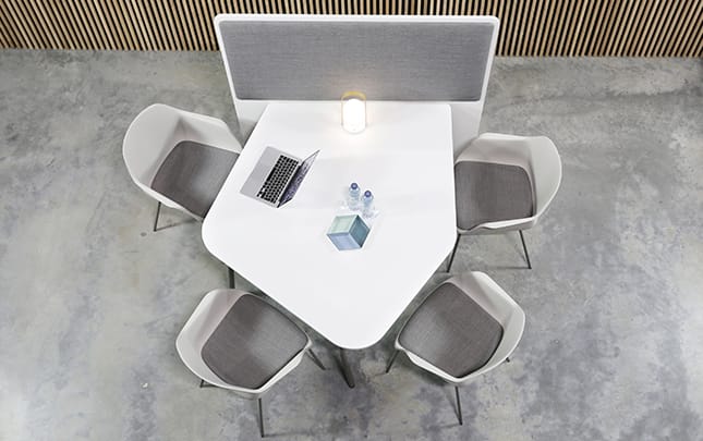 A table with office screen dividers attached and chairs in a room
