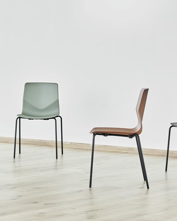 Four different coloured chairs in an empty room.