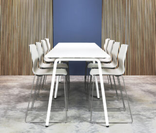 A white standing height tables and chairs in front of a wooden wall.