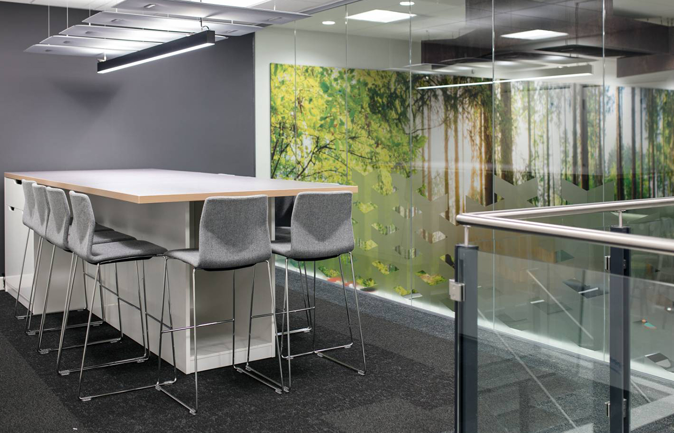 An office with a glass wall and counter chairs.