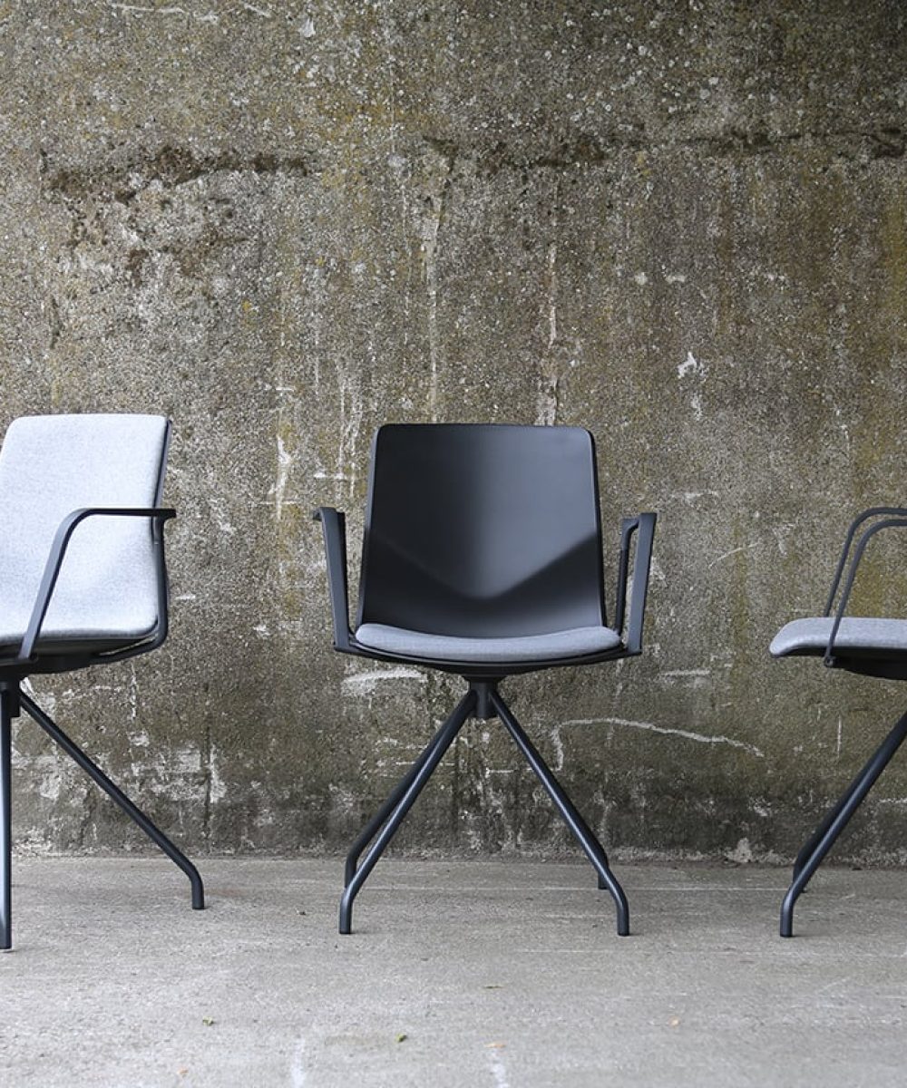 Three grey chairs against a concrete wall.