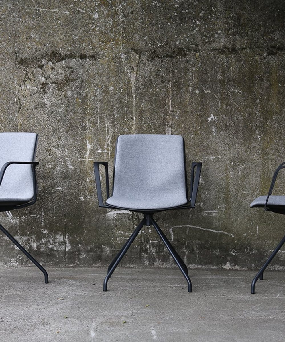 Three grey chairs against a concrete wall.