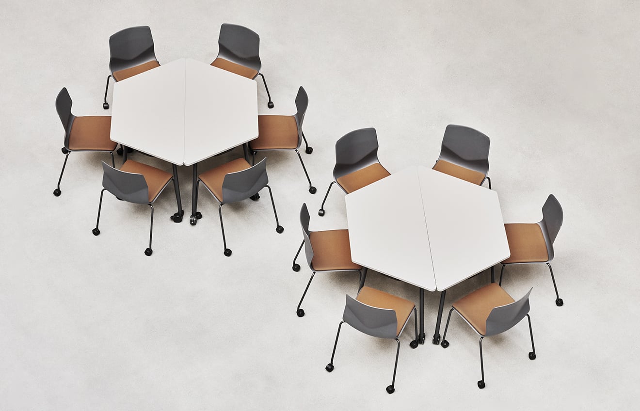 A group of office desk chairs and office tables in a room.