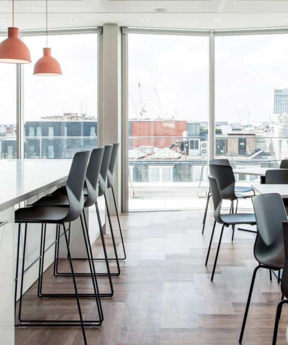 A kitchen with counter chairs and a view of the city.