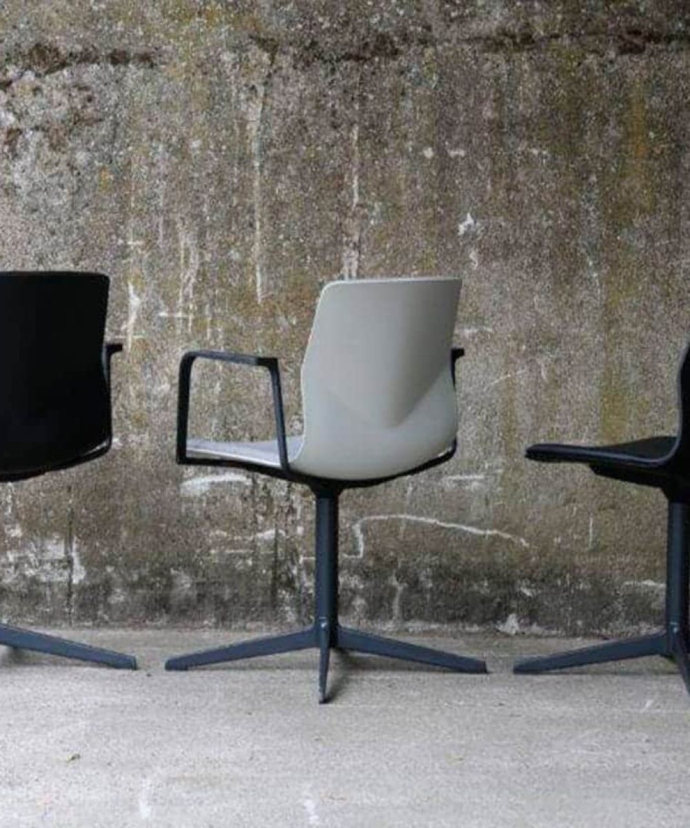 Three black and white chairs in front of a concrete wall.