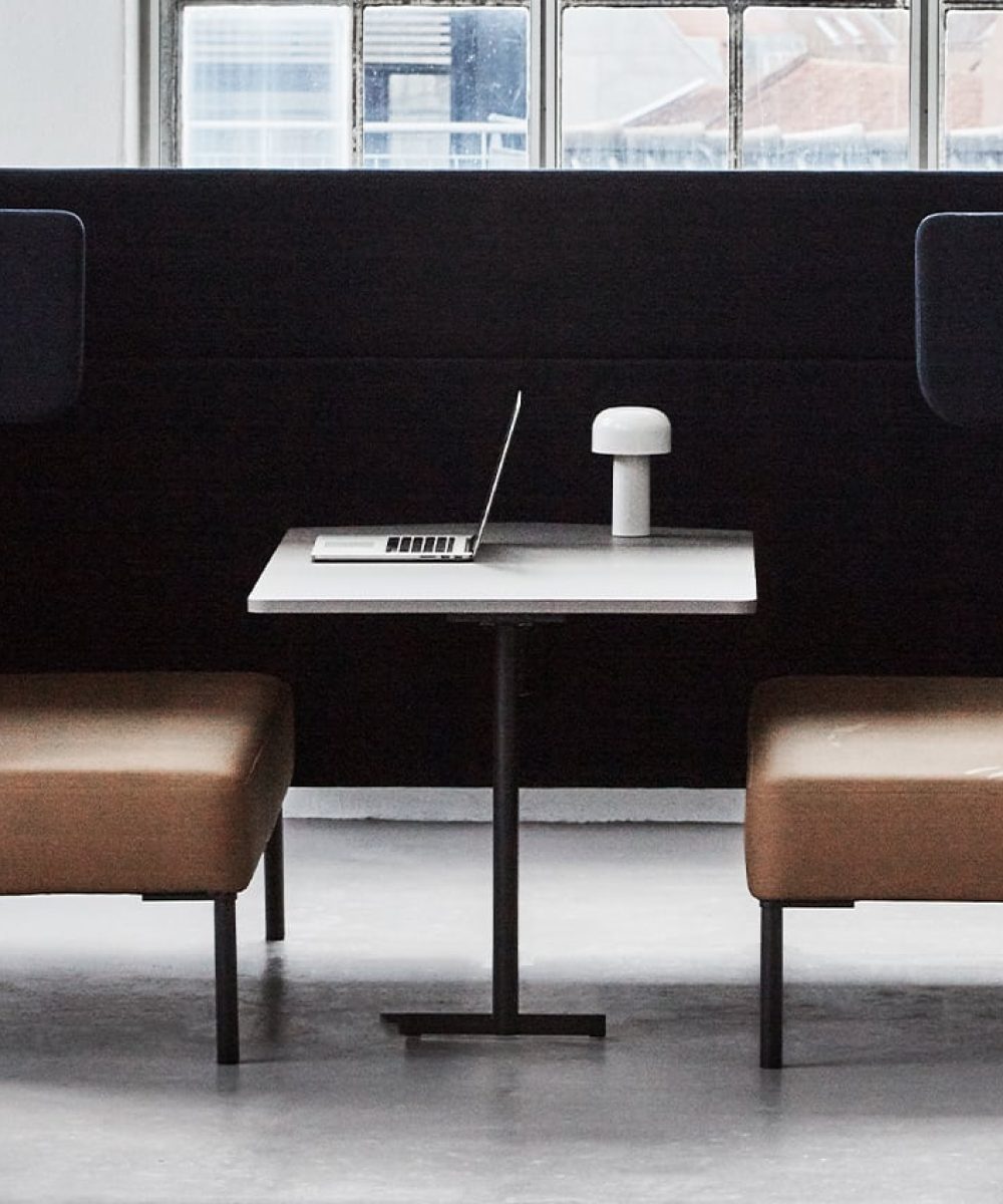 Black office work booth with a white pedestal table.