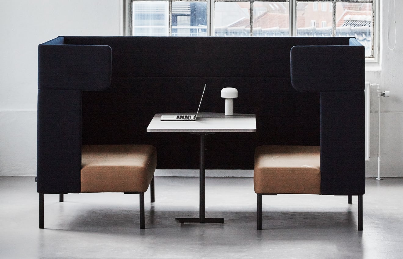 Black office work booth with a white pedestal table.