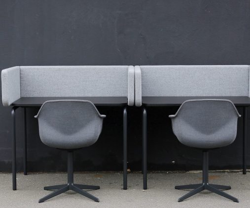 Two grey chairs and desk workstations against a wall.