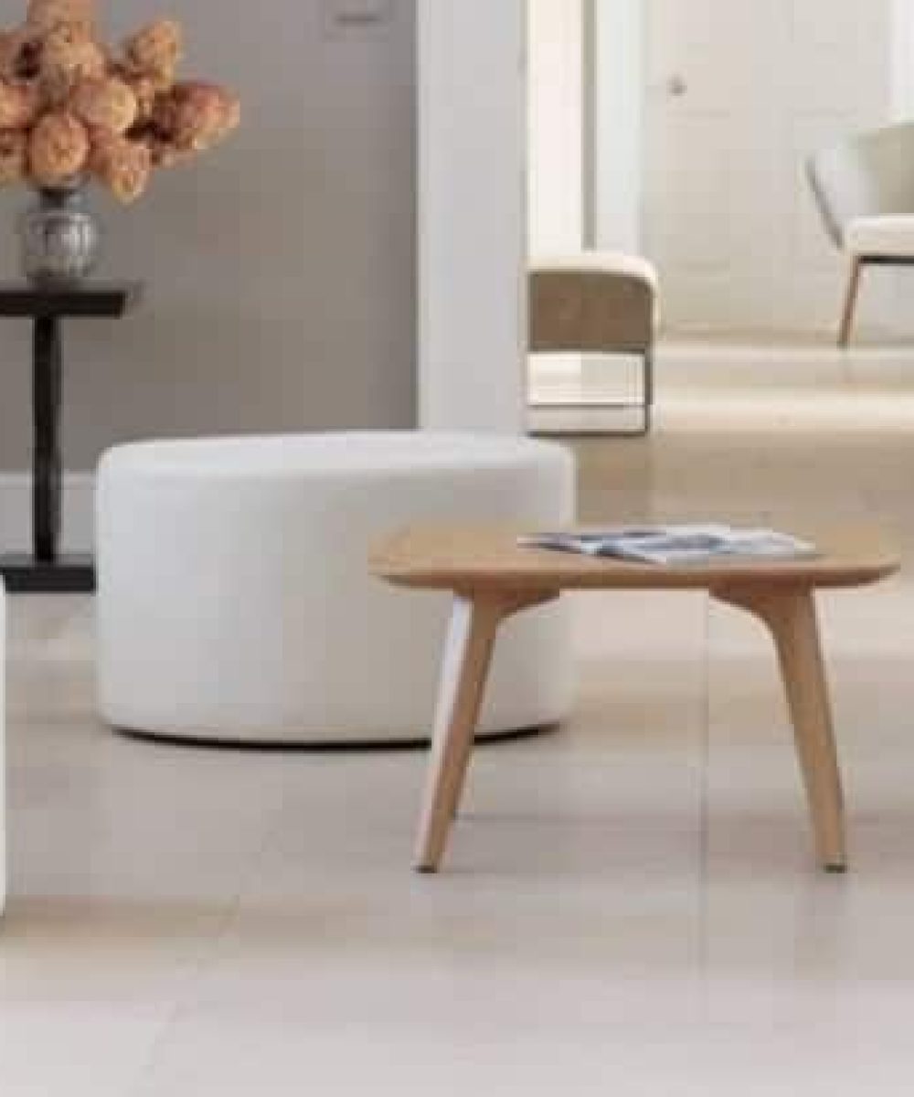 A reception room with white office furniture and a white ottoman.