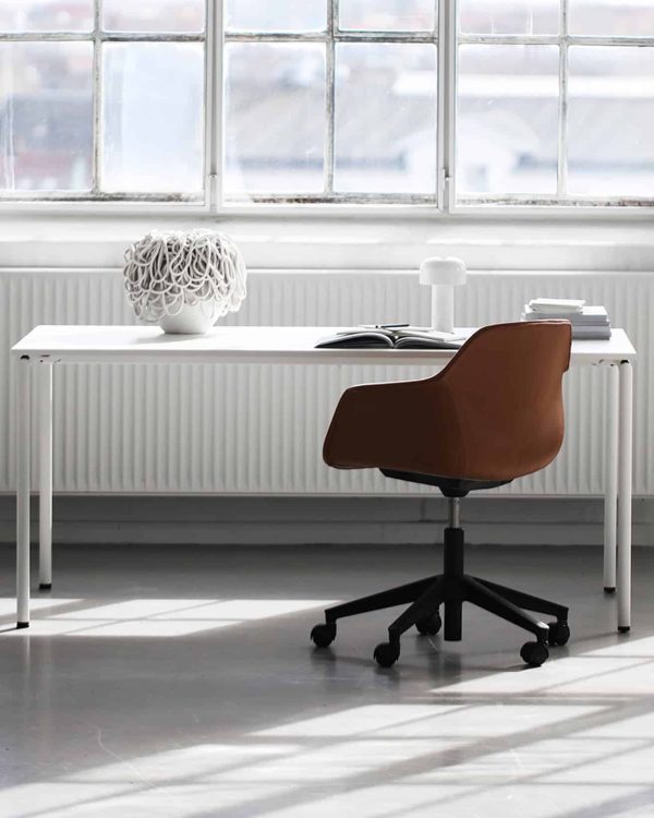 A white desk with an orange chair in front of a window.