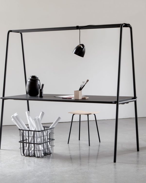 A black community table with a black desk in a white room