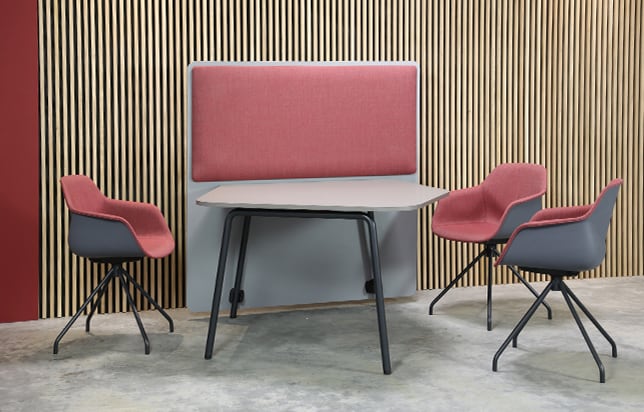 Four office desk chairs and a table with office screen dividers in a conference room.