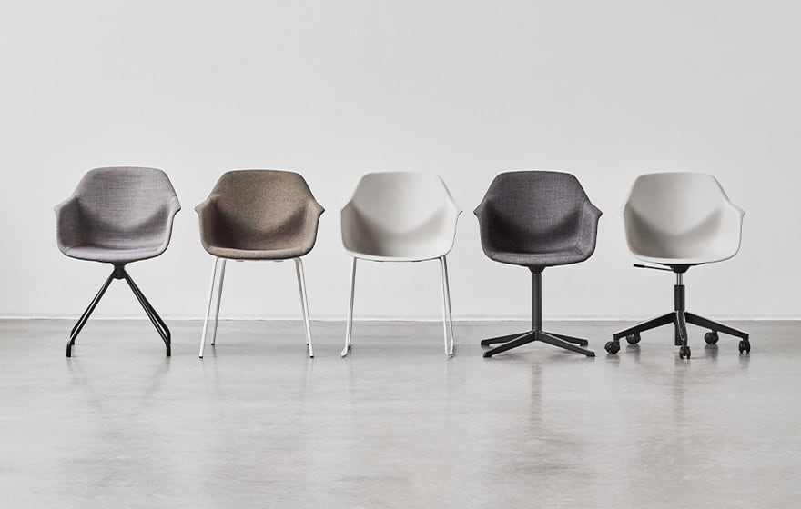 Five chairs in a row in a white room with different seats and different leg configurations