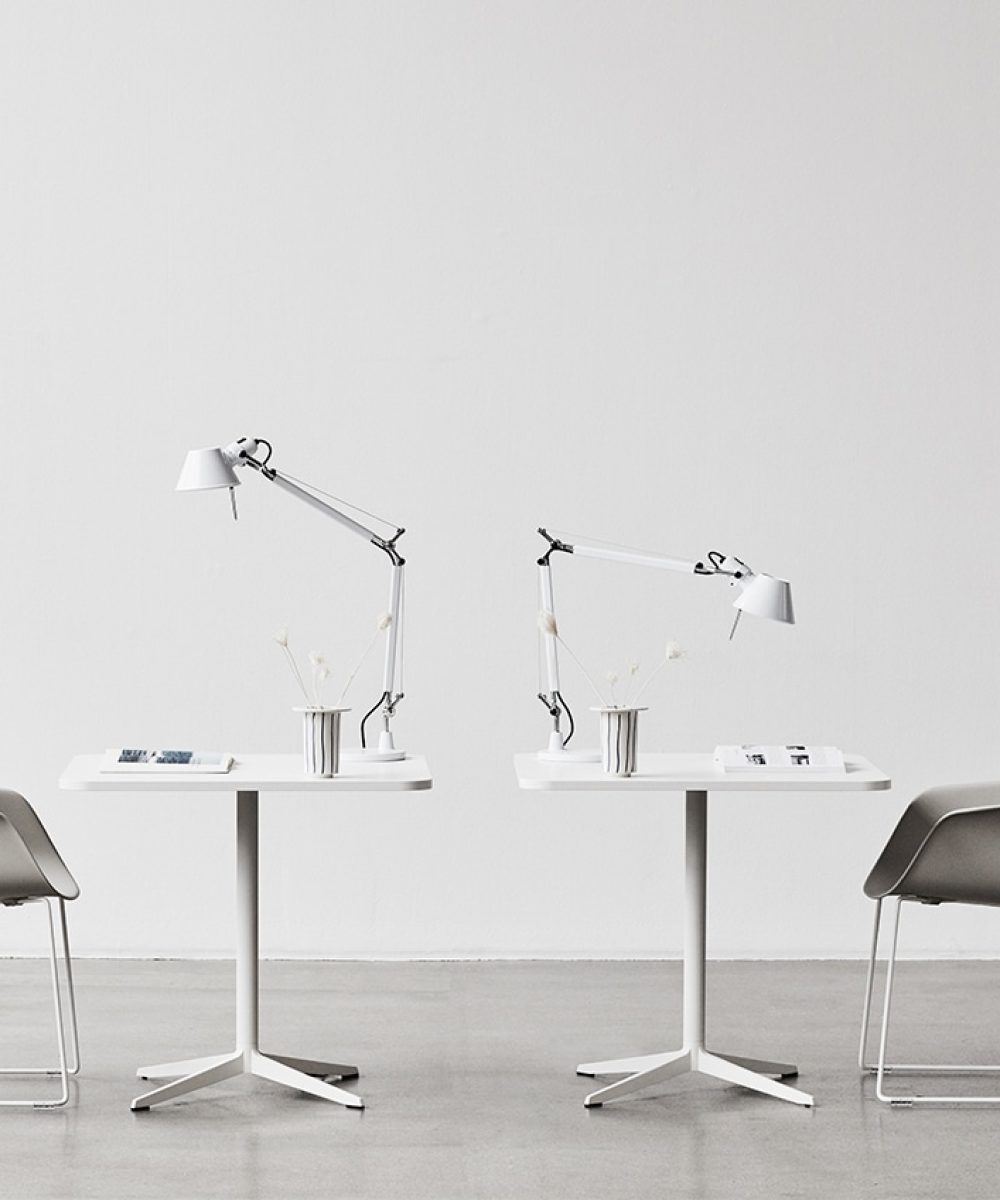 Two people walking in front of a white table.