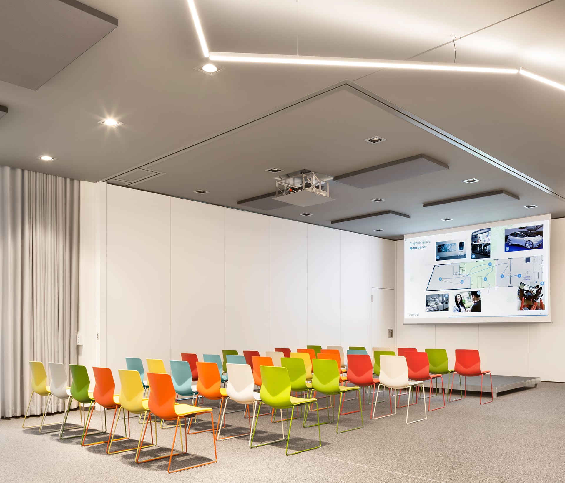 A conference room with colourful chairs and a projector screen.