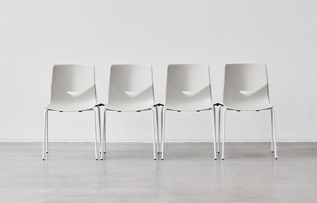 A row of white interlocking white office desk chairs