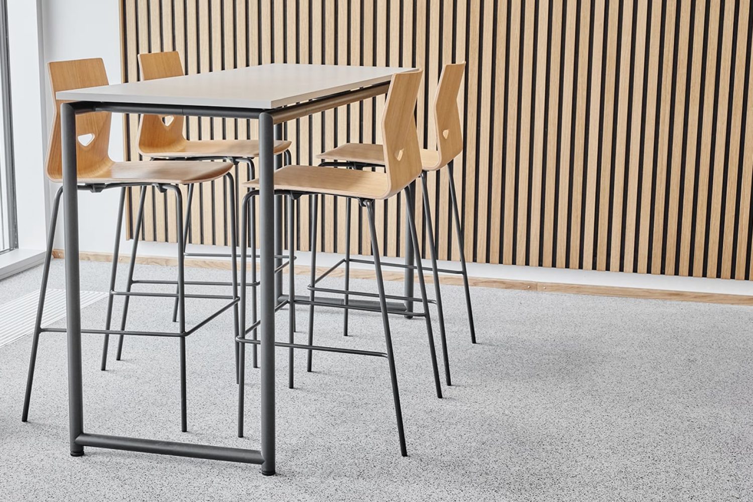 A white conference standing height table with counter chairs around it. 