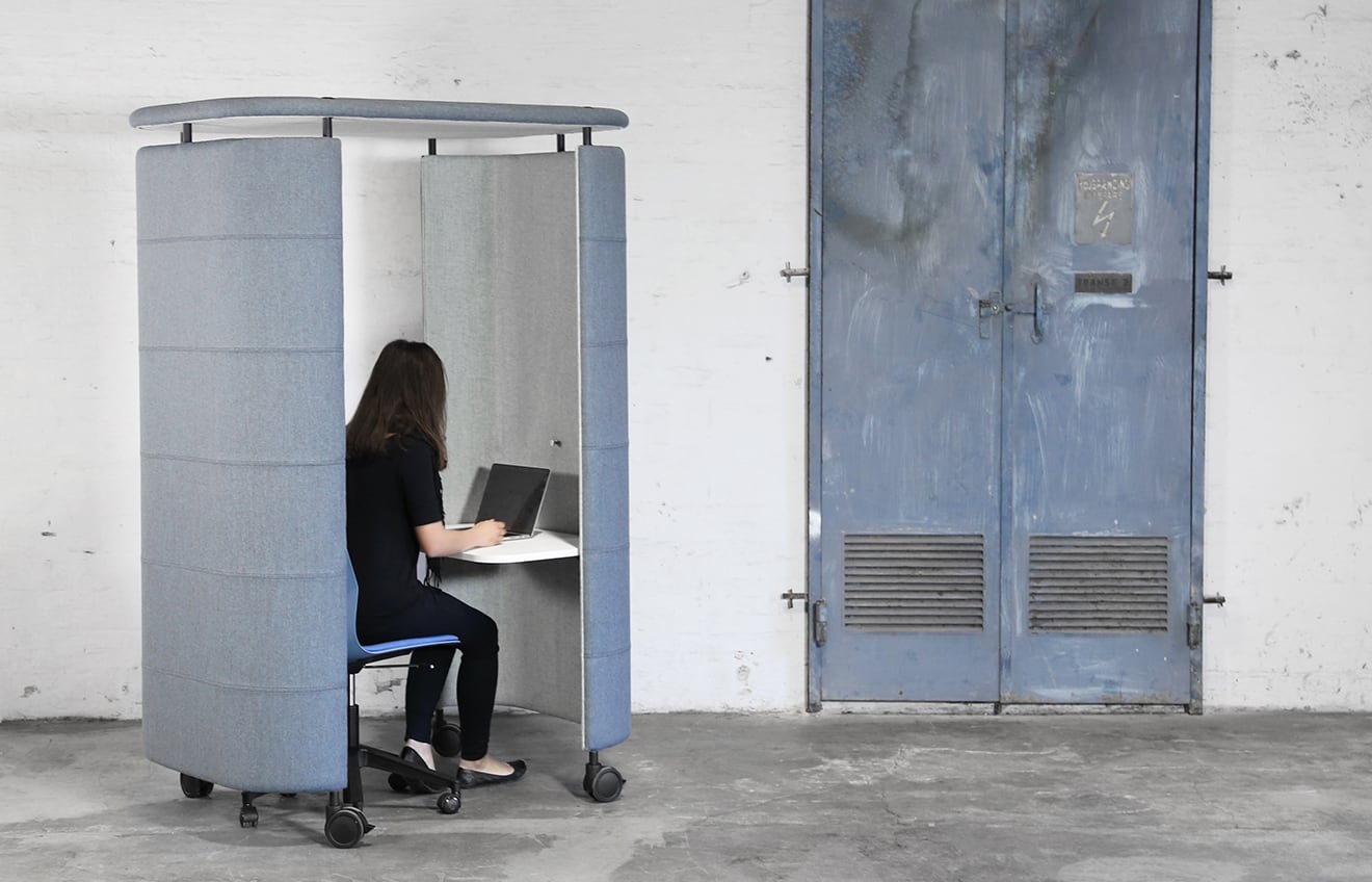 blue office work booth with woman on laptop