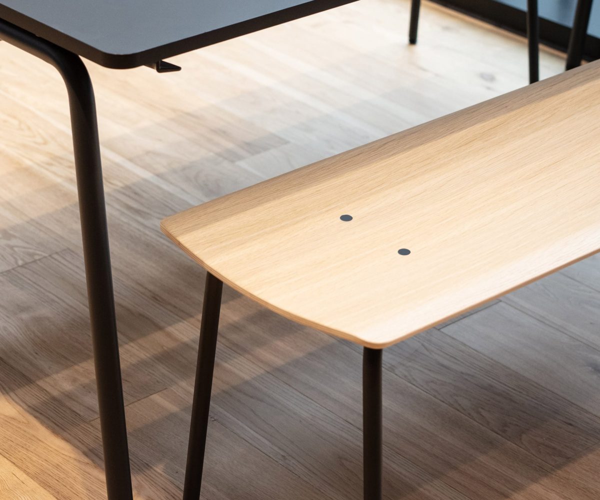 A wooden bench with a black top and black legs.