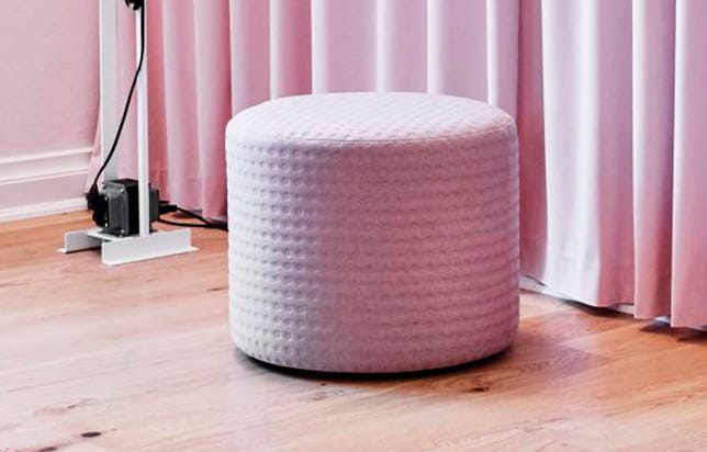 A pink stool in front of a pink curtain.