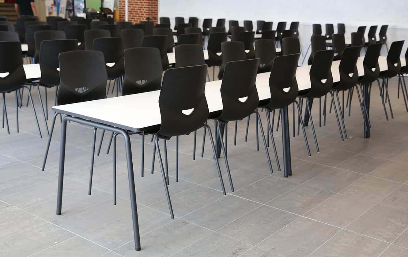 A long row of black chairs in a classroom.
