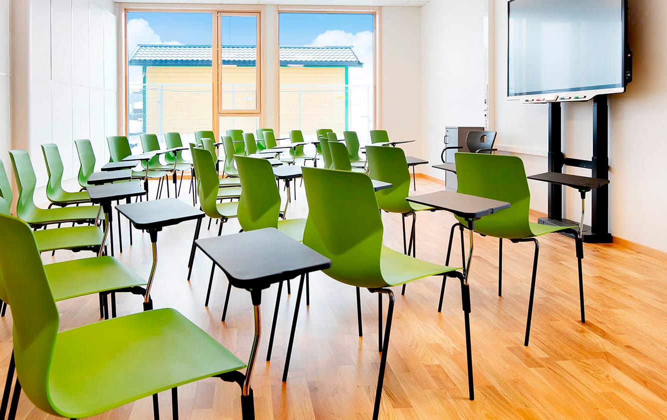 Green chairs with desk attached in a classroom.