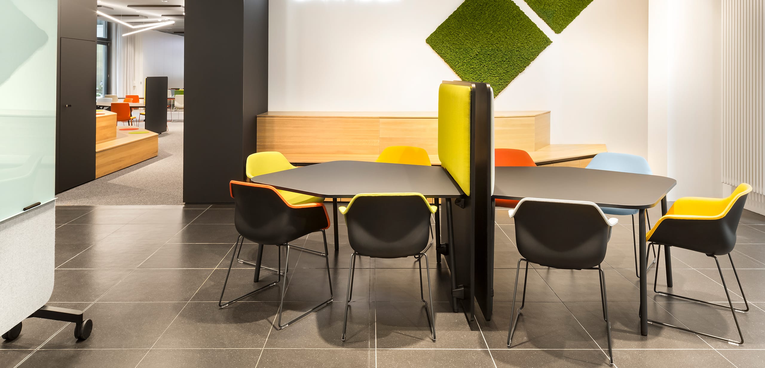 A meeting room with colourful office desk chairs and office tables and office screen dividers.