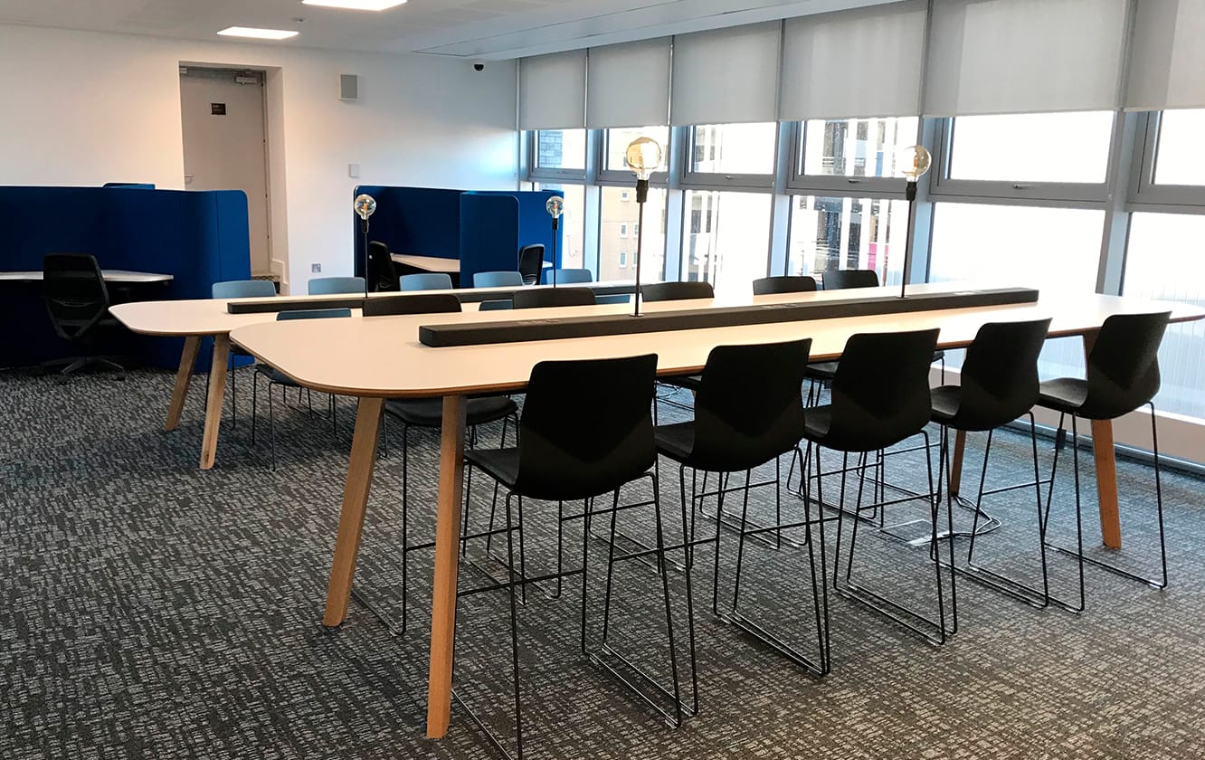 A conference room with a standing height table and counter chairs.