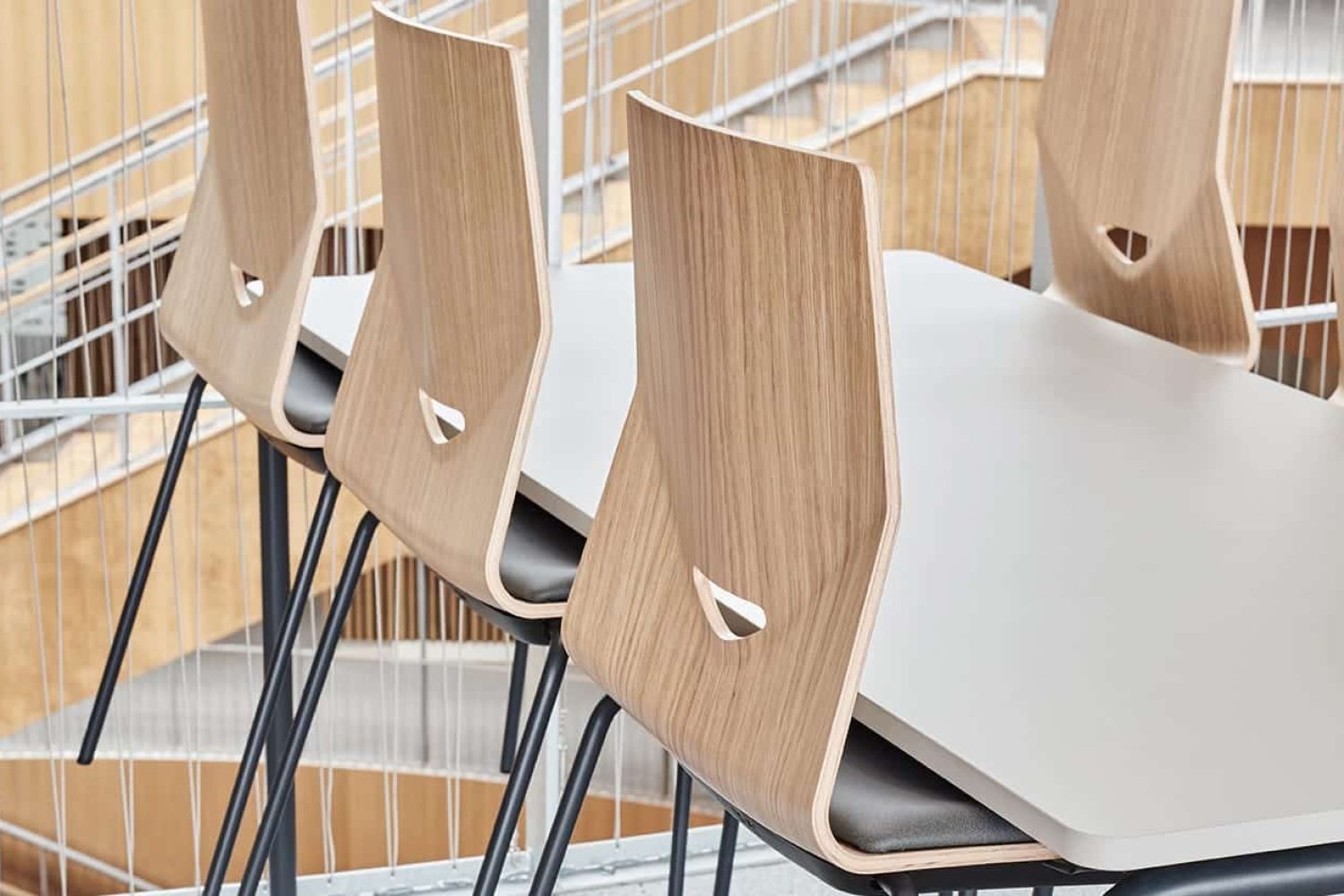 A table with lightweight office chairs in front of a staircase.