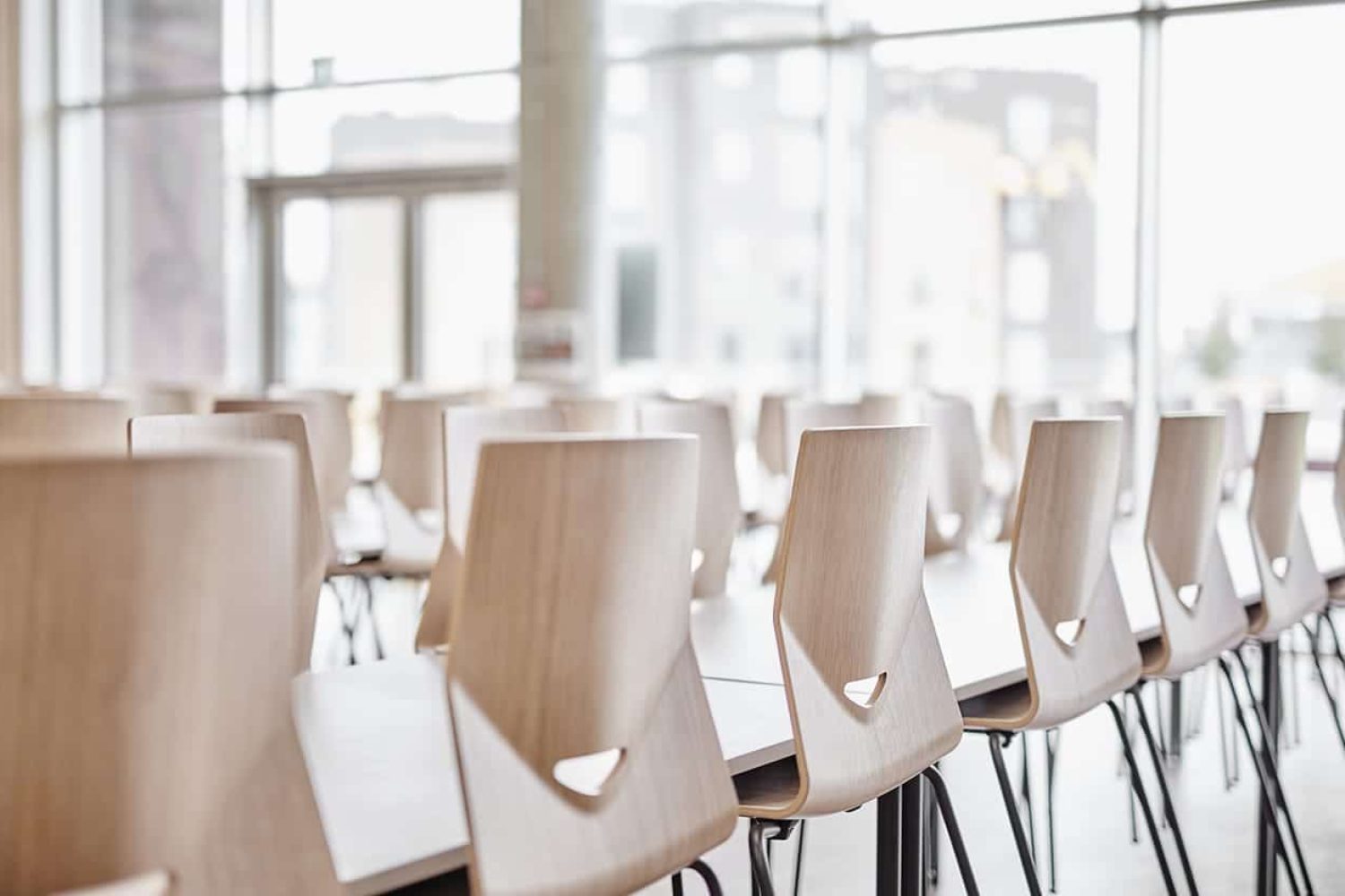 A room with rows of light weight office chairs around desks.