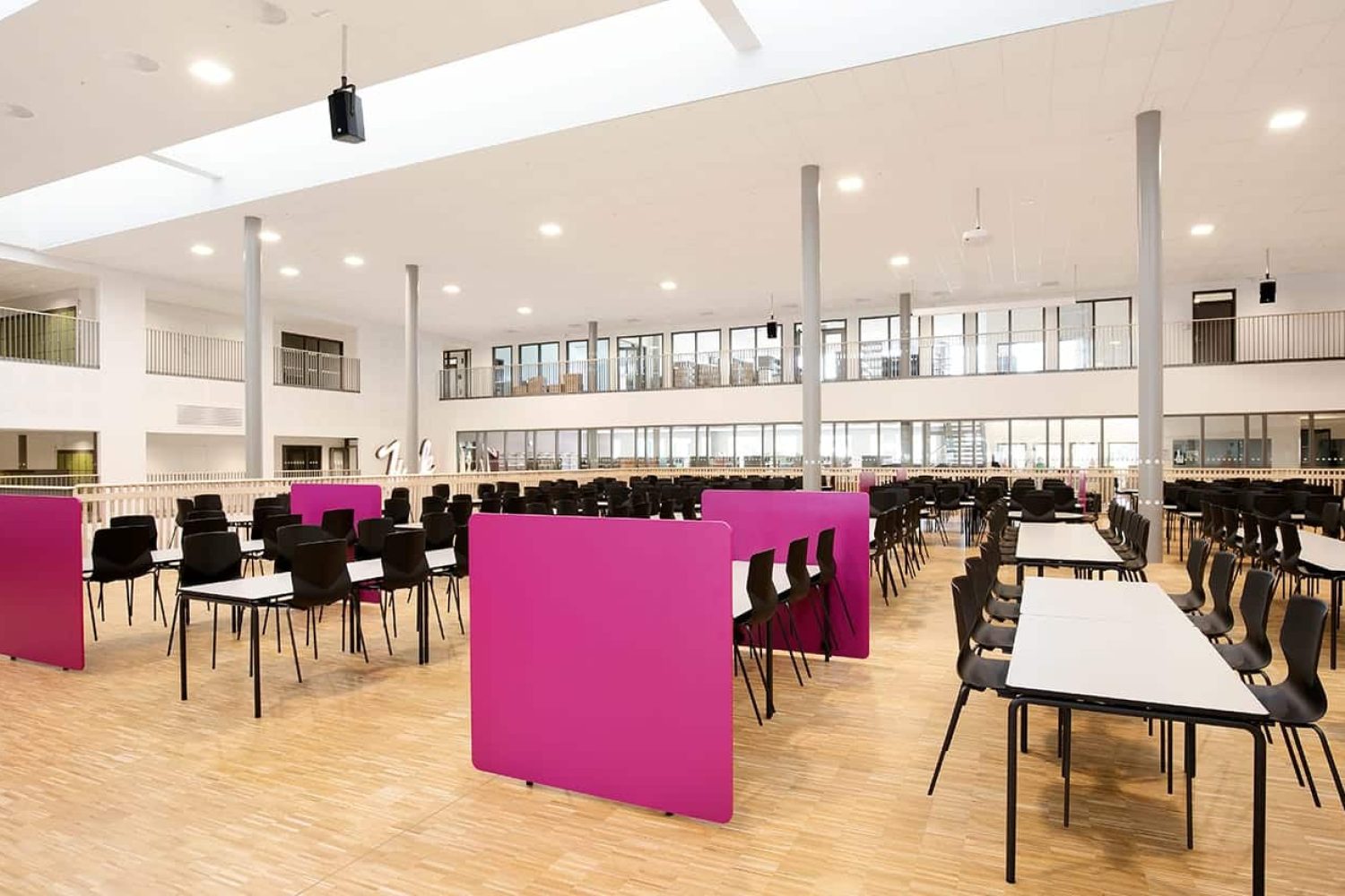 A large room with canteen furniture such as tables and chairs in it.