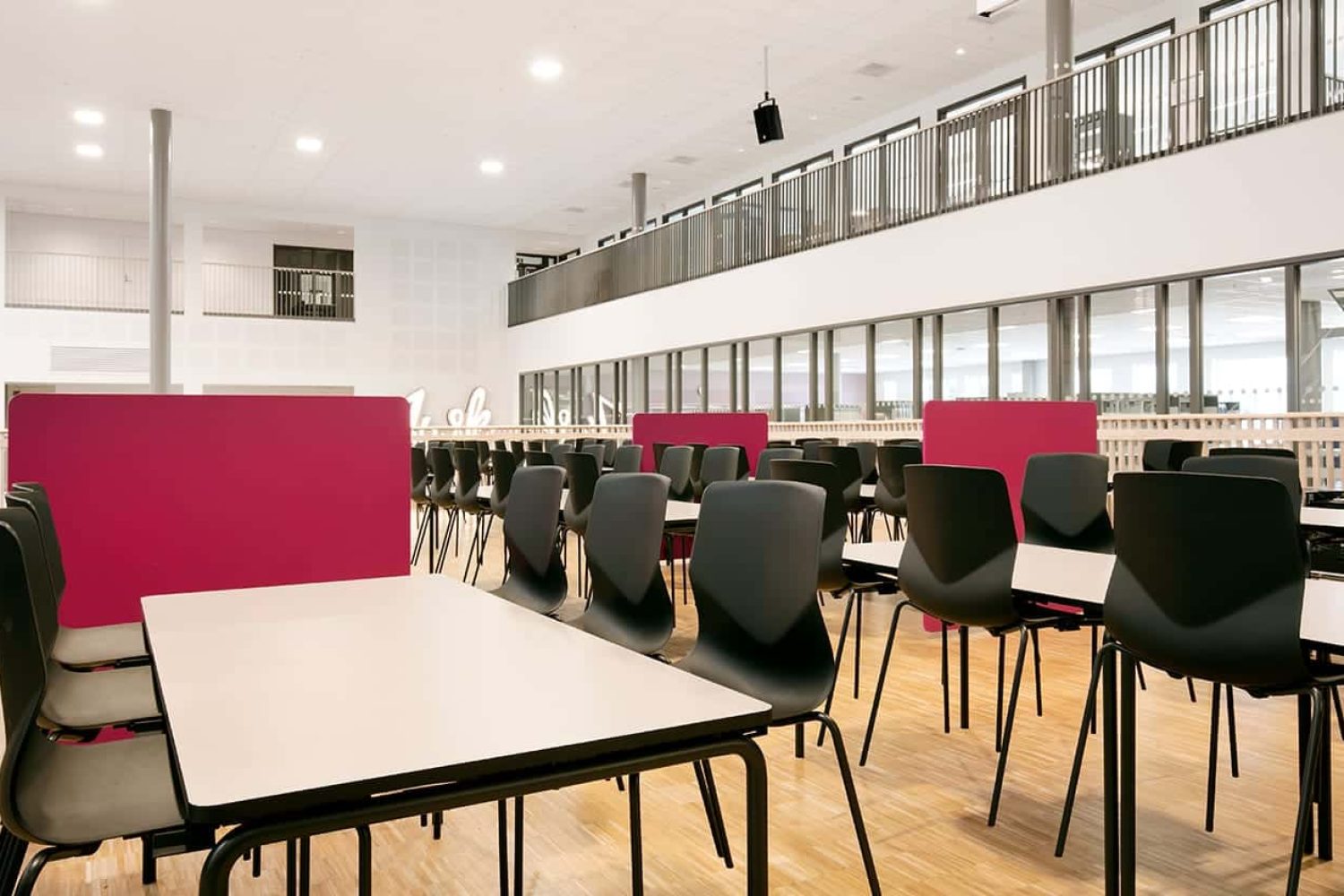 A large room with canteen furniture such as tables and chairs in it.