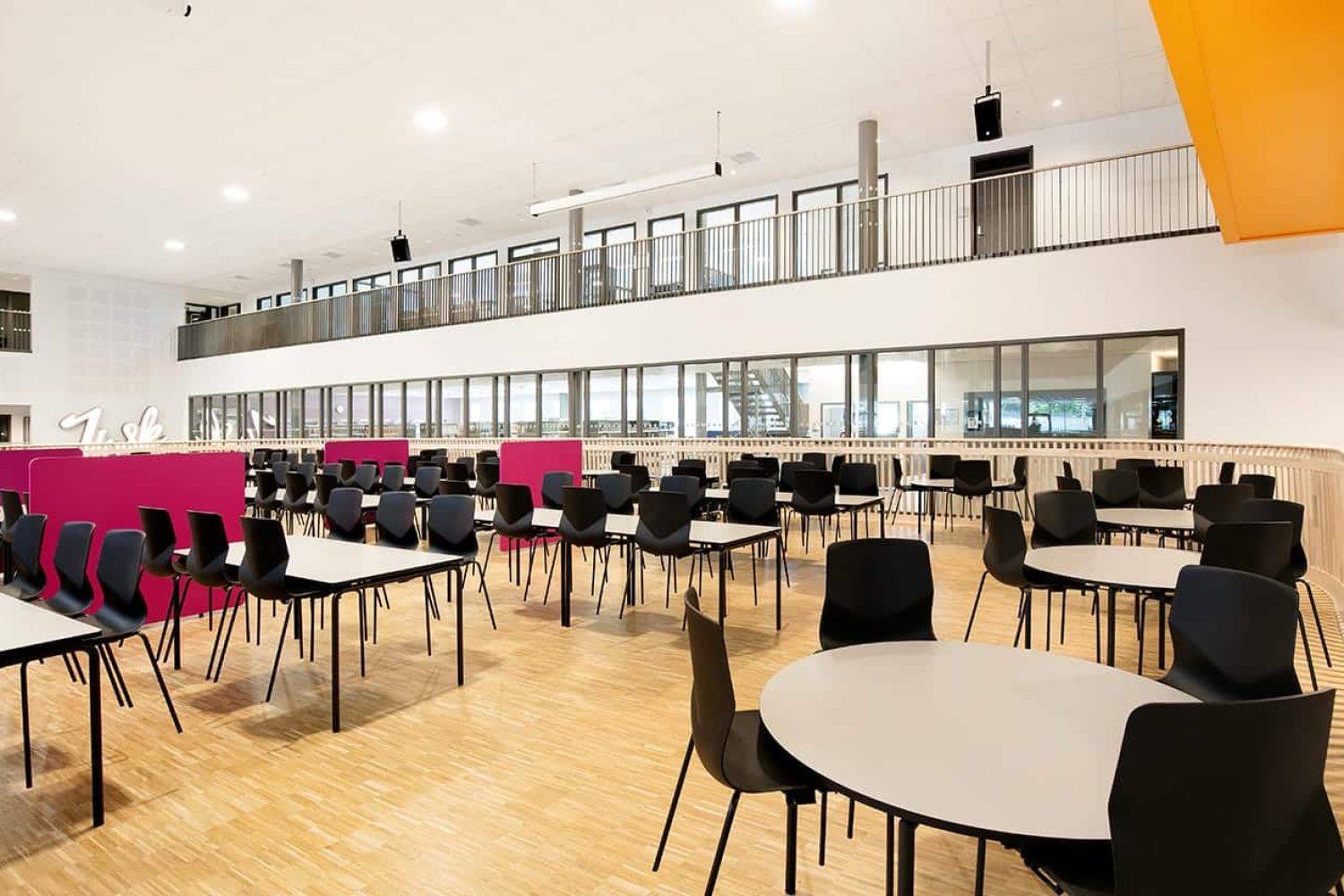 A large room with canteen furniture such as tables and chairs in it.