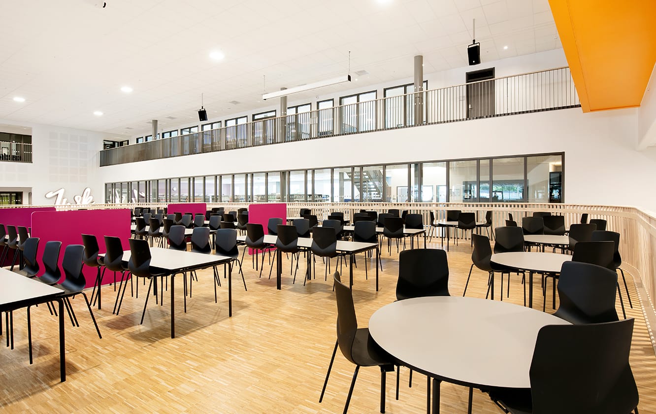 A large room with canteen furniture such as tables and chairs in it.